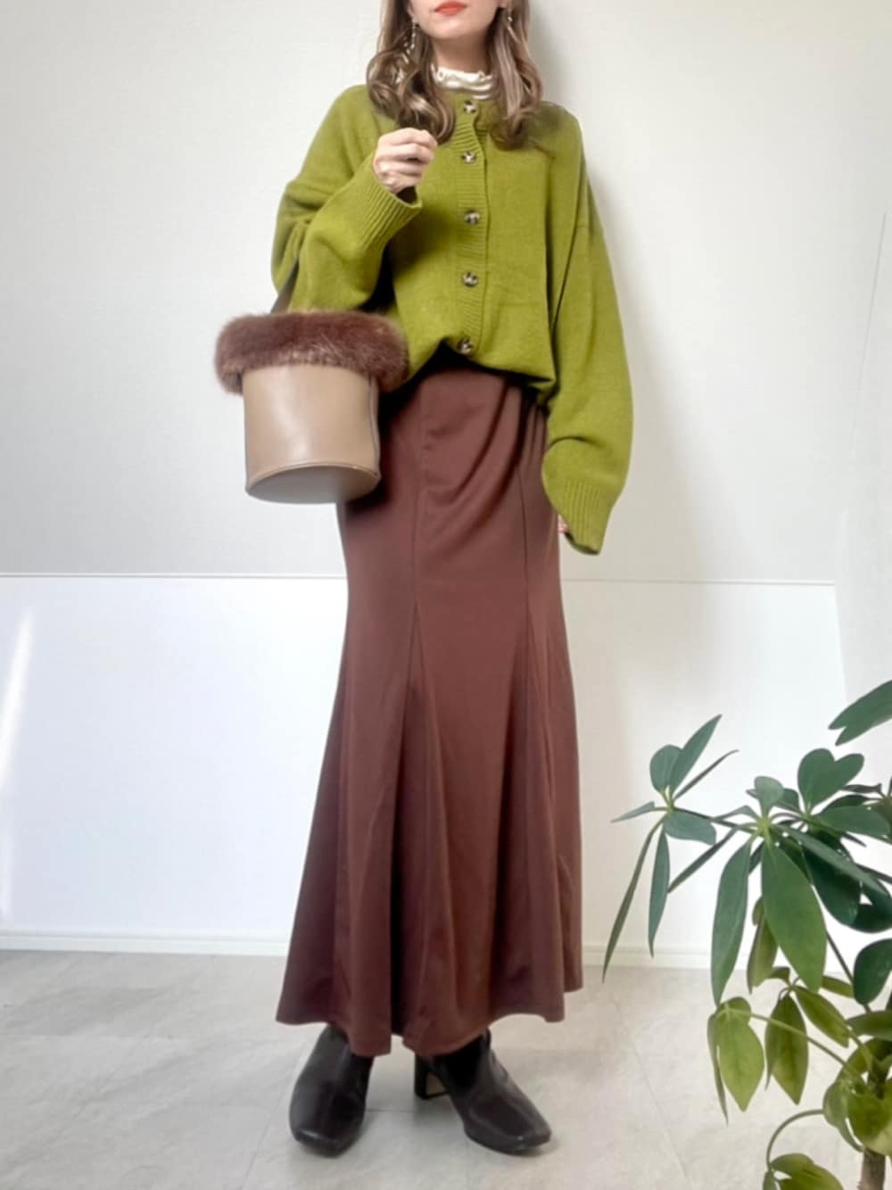 グリーン系のカーディガン/ボレロ、ブラウン系のスカート、ブラウン系のブーツを着用したレディースの秋コーディネートの1枚目の写真