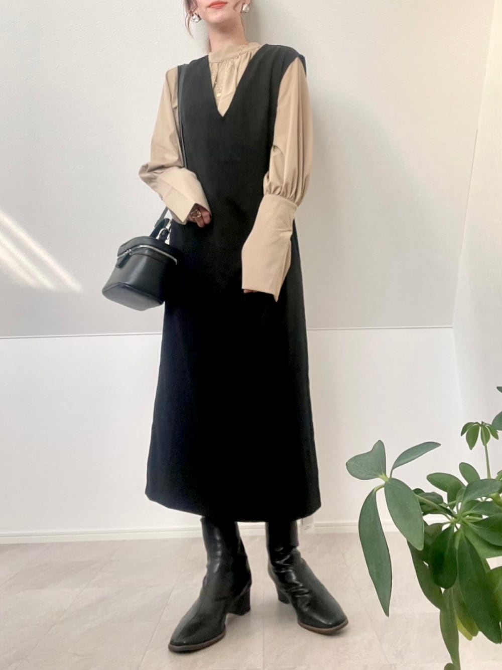 ベージュ系のシャツ/ブラウス、ブラック系のジャンパースカート、ブラック系のハンドバッグを着用したレディースの冬コーディネートの1枚目の写真