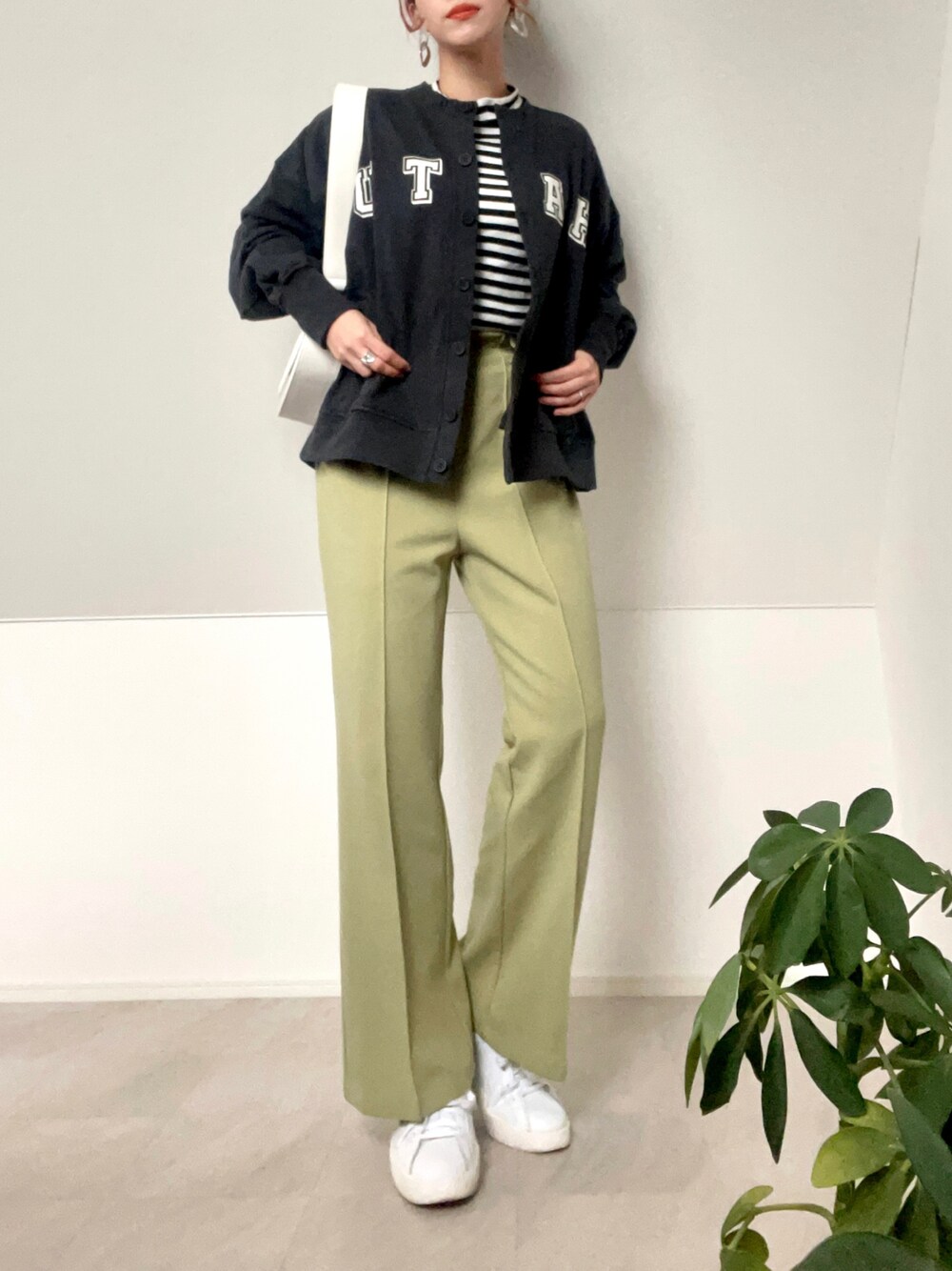 ブラック系のカーディガン/ボレロ、ホワイト系のショルダーバッグ、グリーン系のパンツを着用したレディースの冬コーディネートの1枚目の写真