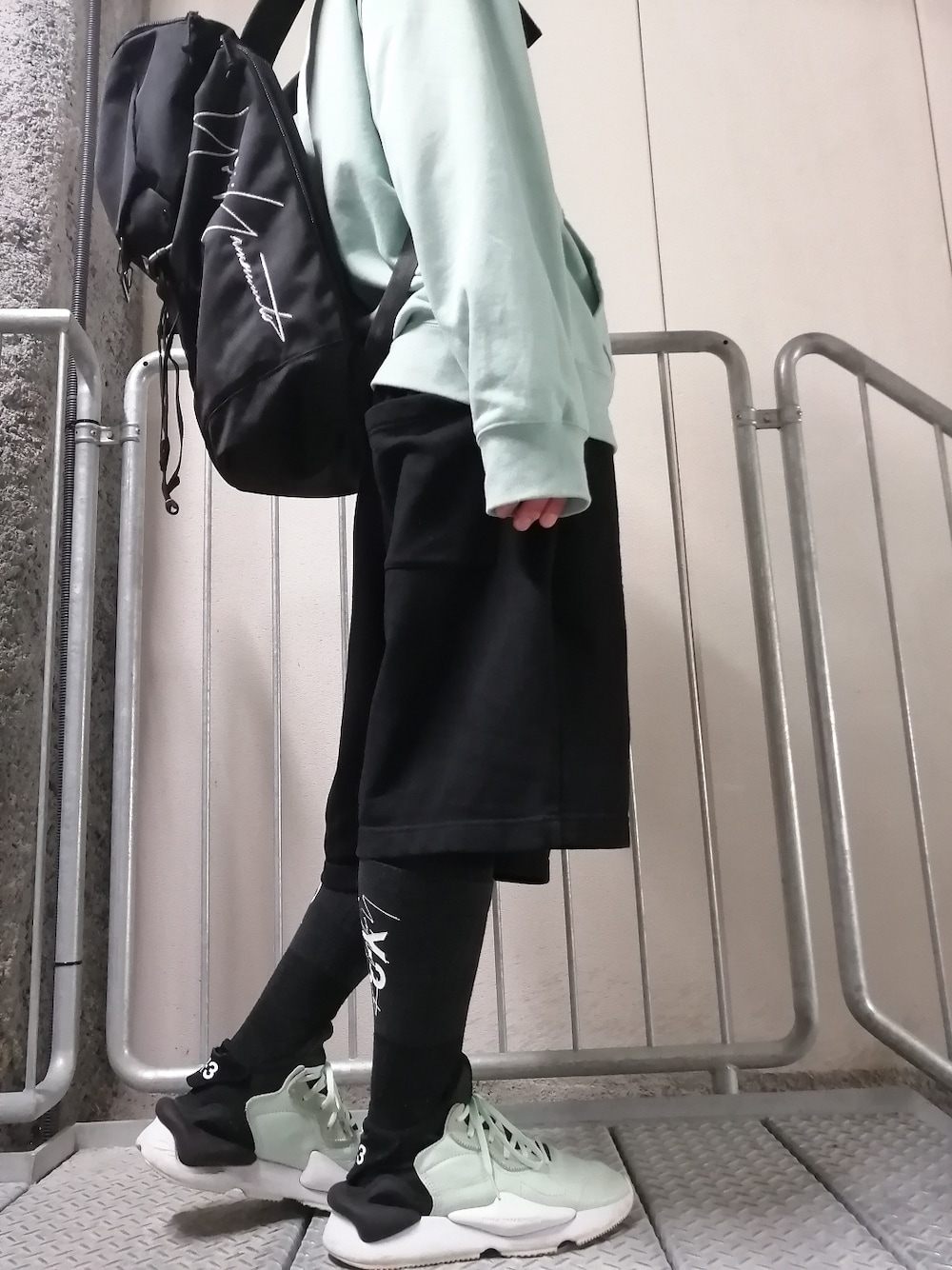 グリーン系のスニーカー、ブラック系のパンツ、グリーン系のパーカーを着用したメンズの春コーディネートの1枚目の写真