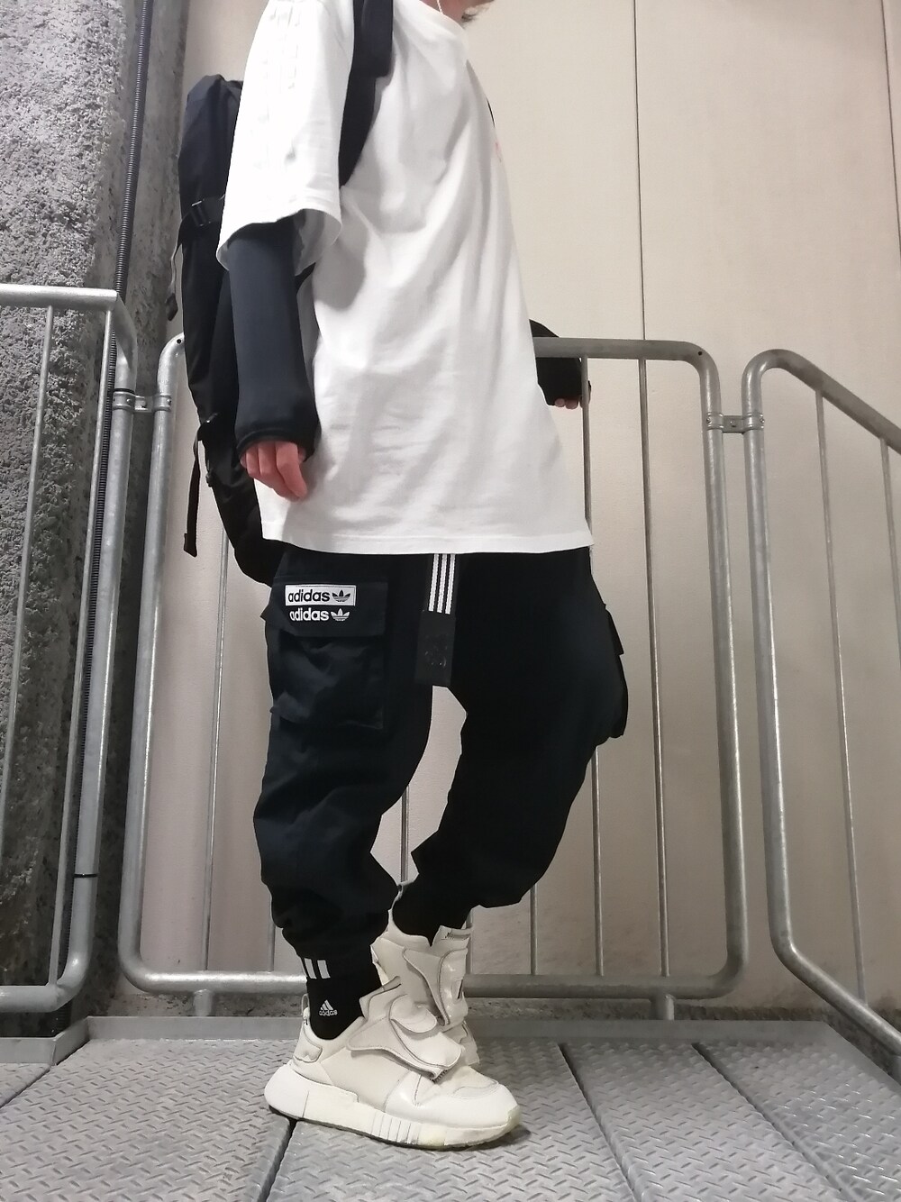 ホワイト系のスニーカー、ブラック系のカーゴパンツ、ホワイト系のトップスを着用したメンズの春コーディネートの1枚目の写真