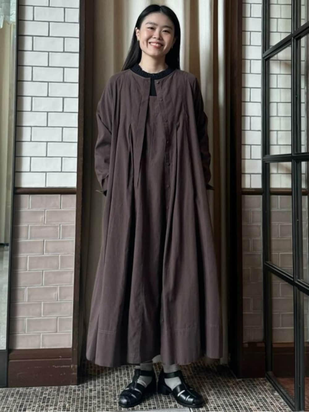 ブラウン系のジャンパースカート、ブラウン系のワンピース、ブラック系のTシャツ/カットソーを着用したレディースの秋コーディネートの1枚目の写真