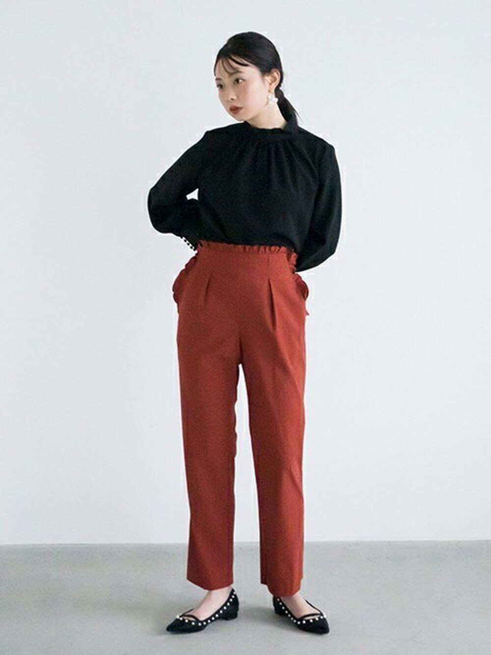ブラック系のシャツ/ブラウス、レッド系のスラックス、ブラック系のパンプスを着用したレディースの春コーディネートの1枚目の写真