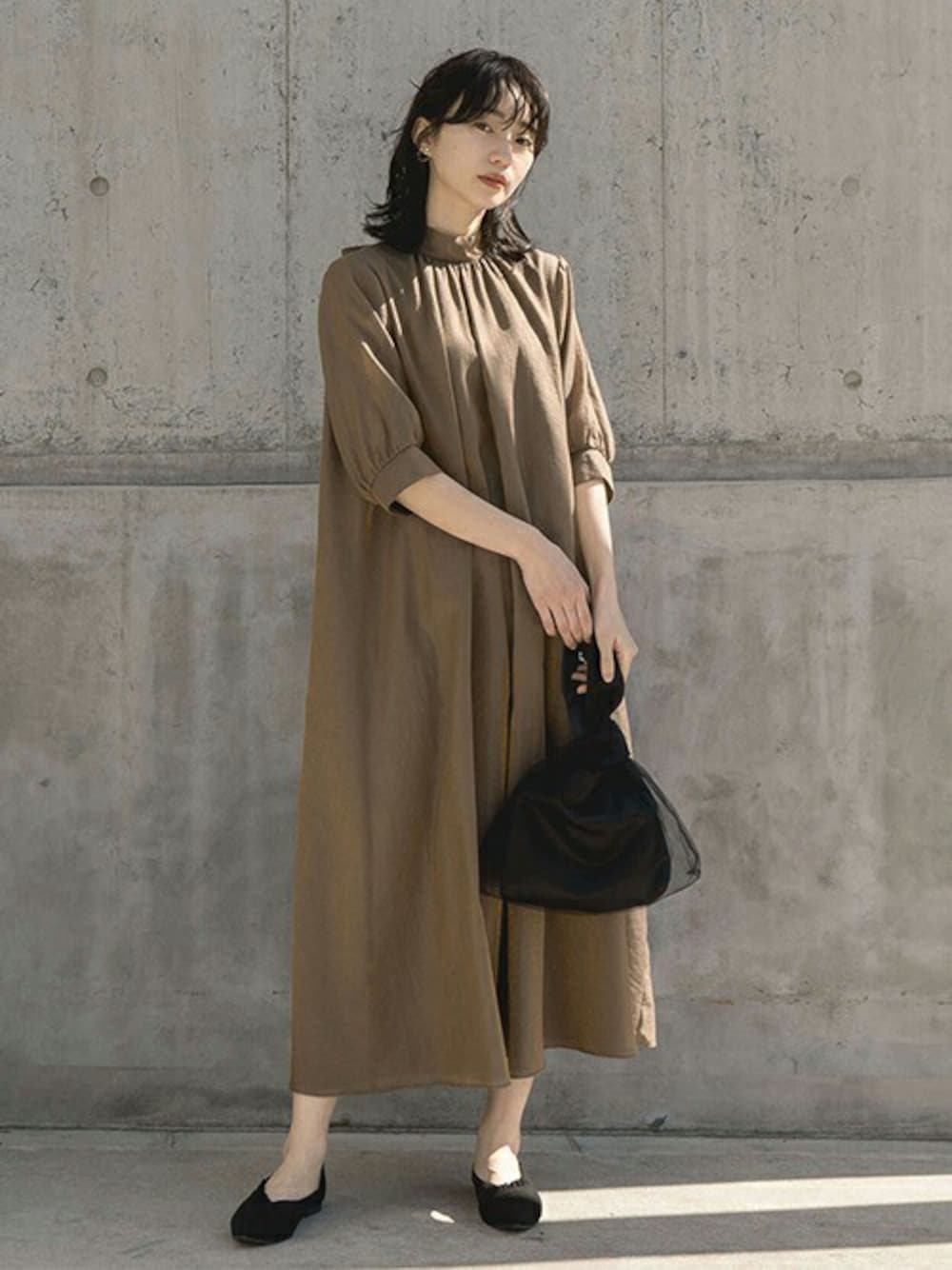 ブラウン系のドレス、ブラック系のハンドバッグ、ブラック系のパンプスを着用したレディースの春コーディネートの1枚目の写真