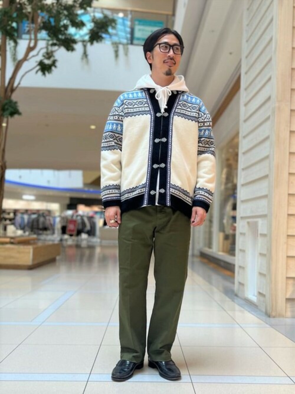 ブルー系のカーディガン/ボレロ、グリーン系のチノパンツ、グレー系のパーカーを着用したメンズの冬コーディネートの1枚目の写真