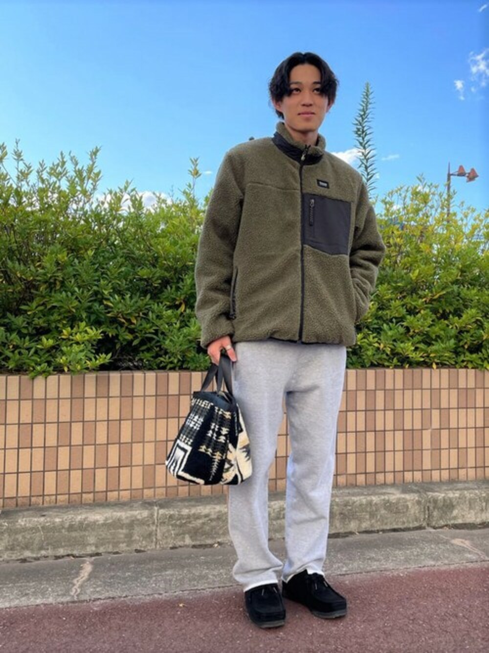 ブルー系のブルゾン、グレー系のその他パンツ、ブラック系のトートバッグを着用したメンズの冬コーディネートの1枚目の写真