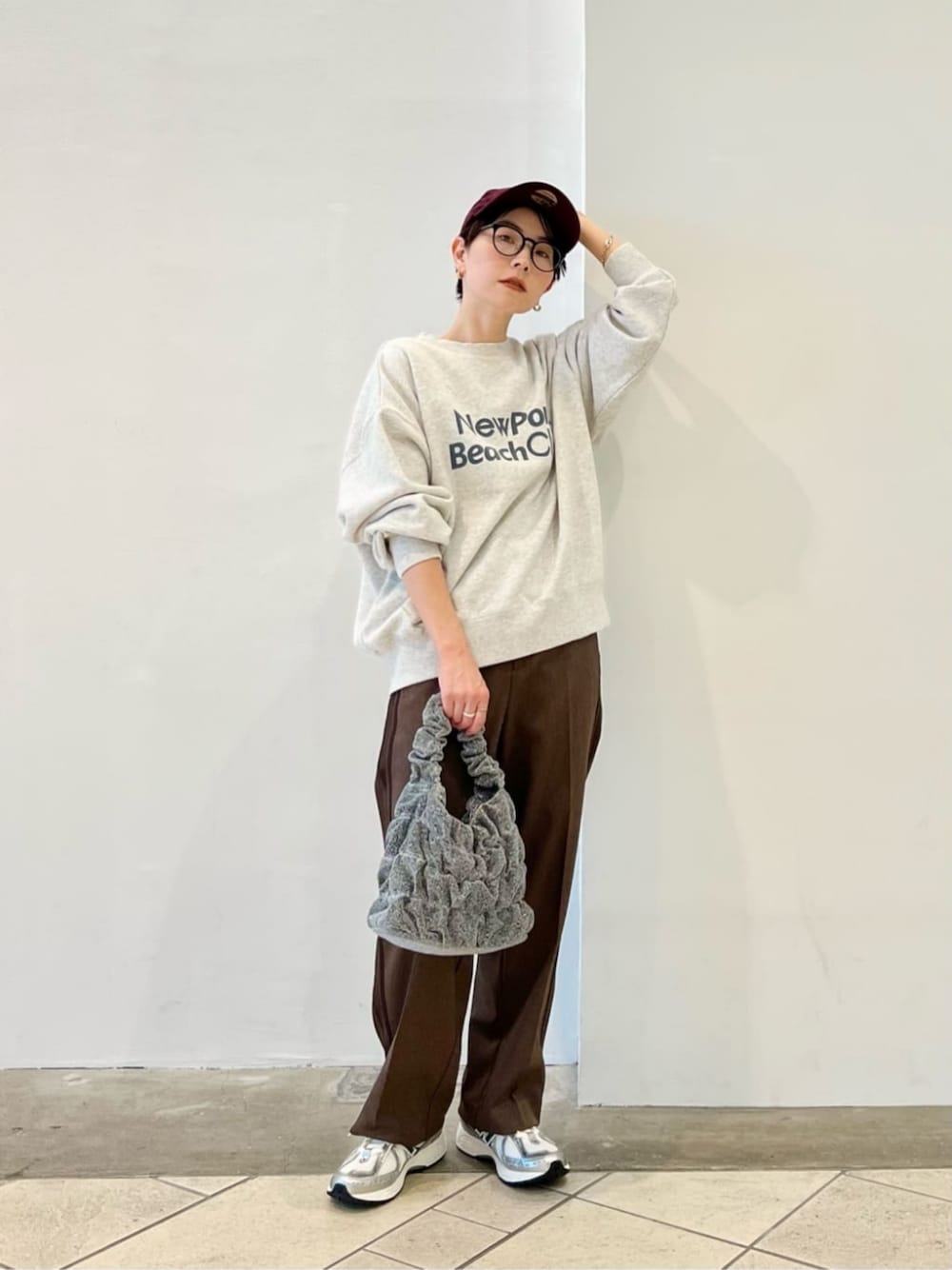 グレー系のスウェット、ホワイト系のTシャツ/カットソー、ブラウン系のスラックスを着用したレディースの秋コーディネートの1枚目の写真