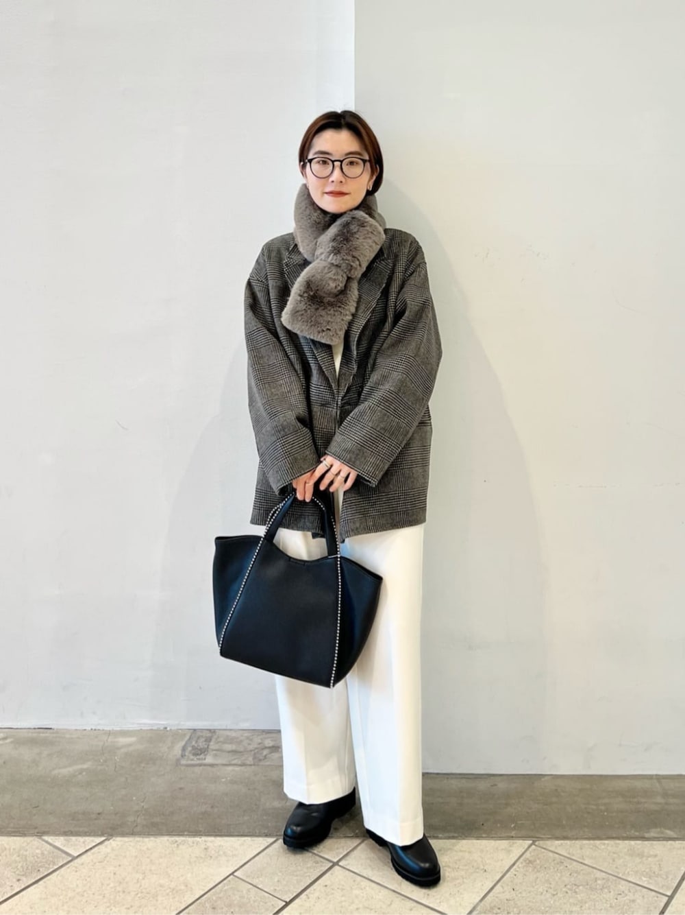 ブラック系のブーツ、ホワイト系のニット/セーター、ホワイト系のスラックスを着用したレディースの冬コーディネートの1枚目の写真