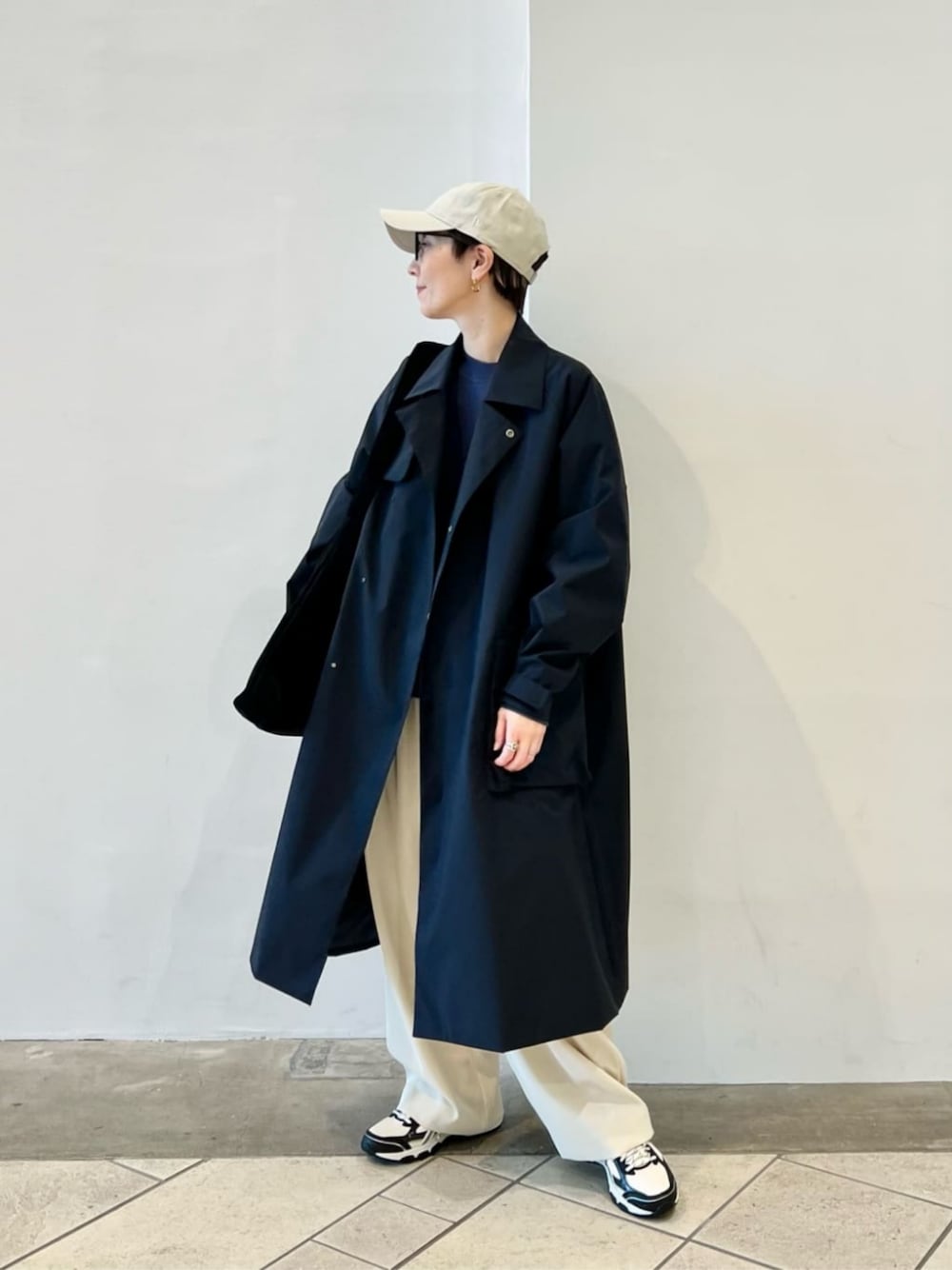 ブラック系のショルダーバッグ、ホワイト系のスラックス、ベージュ系のスニーカーを着用したレディースの秋コーディネートの1枚目の写真