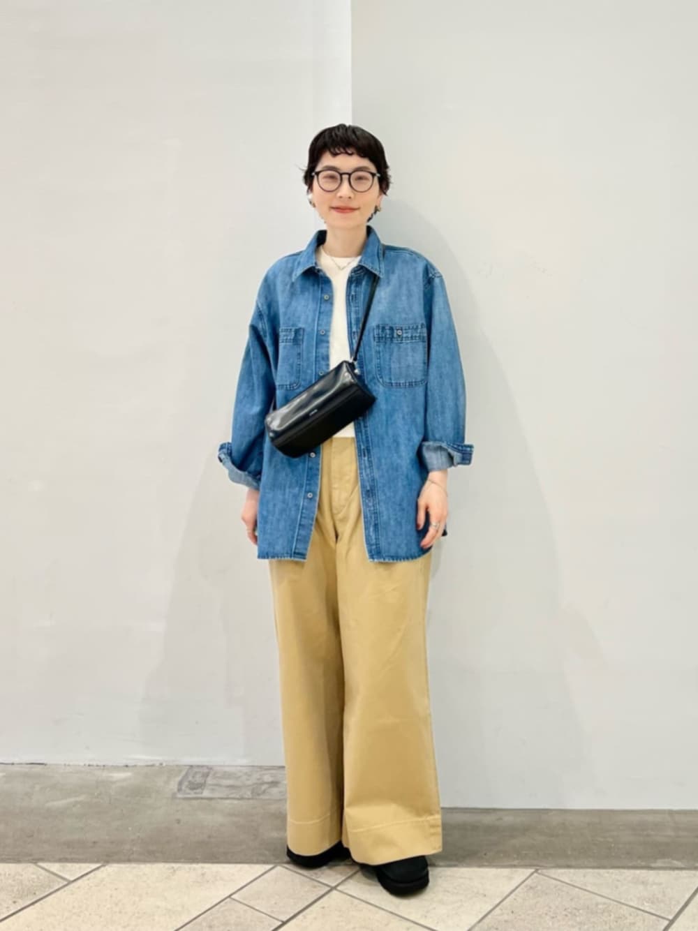 ブルー系のシャツ/ブラウス、ホワイト系のニット/セーター、ベージュ系のチノパンツを着用したレディースの春コーディネートの1枚目の写真