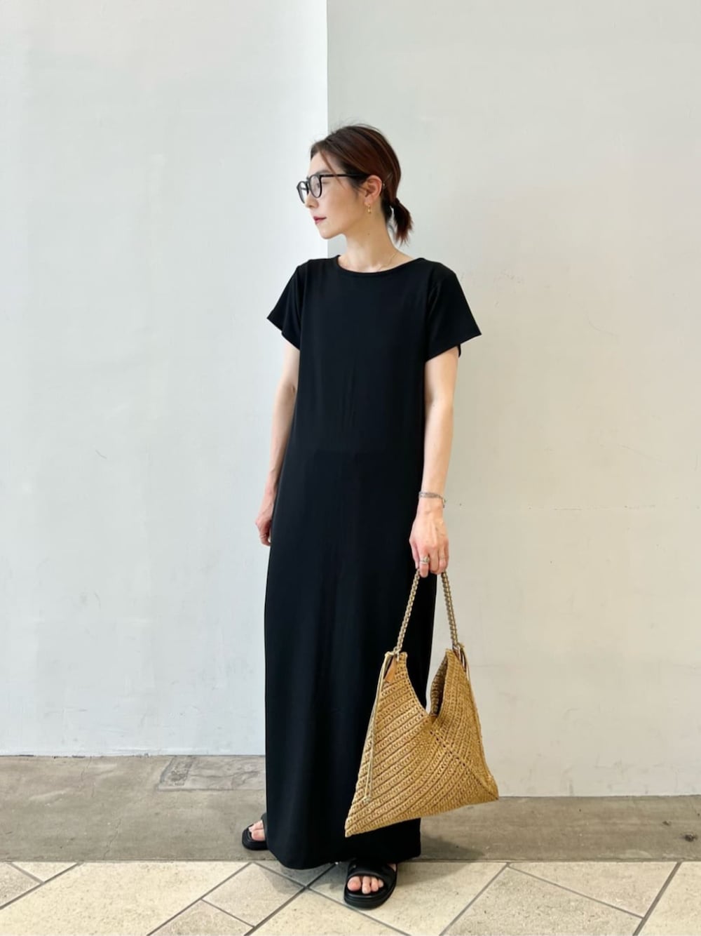 ベージュ系のショルダーバッグ、ブラック系のワンピース、ブラック系のサンダルを着用したレディースの夏コーディネートの1枚目の写真
