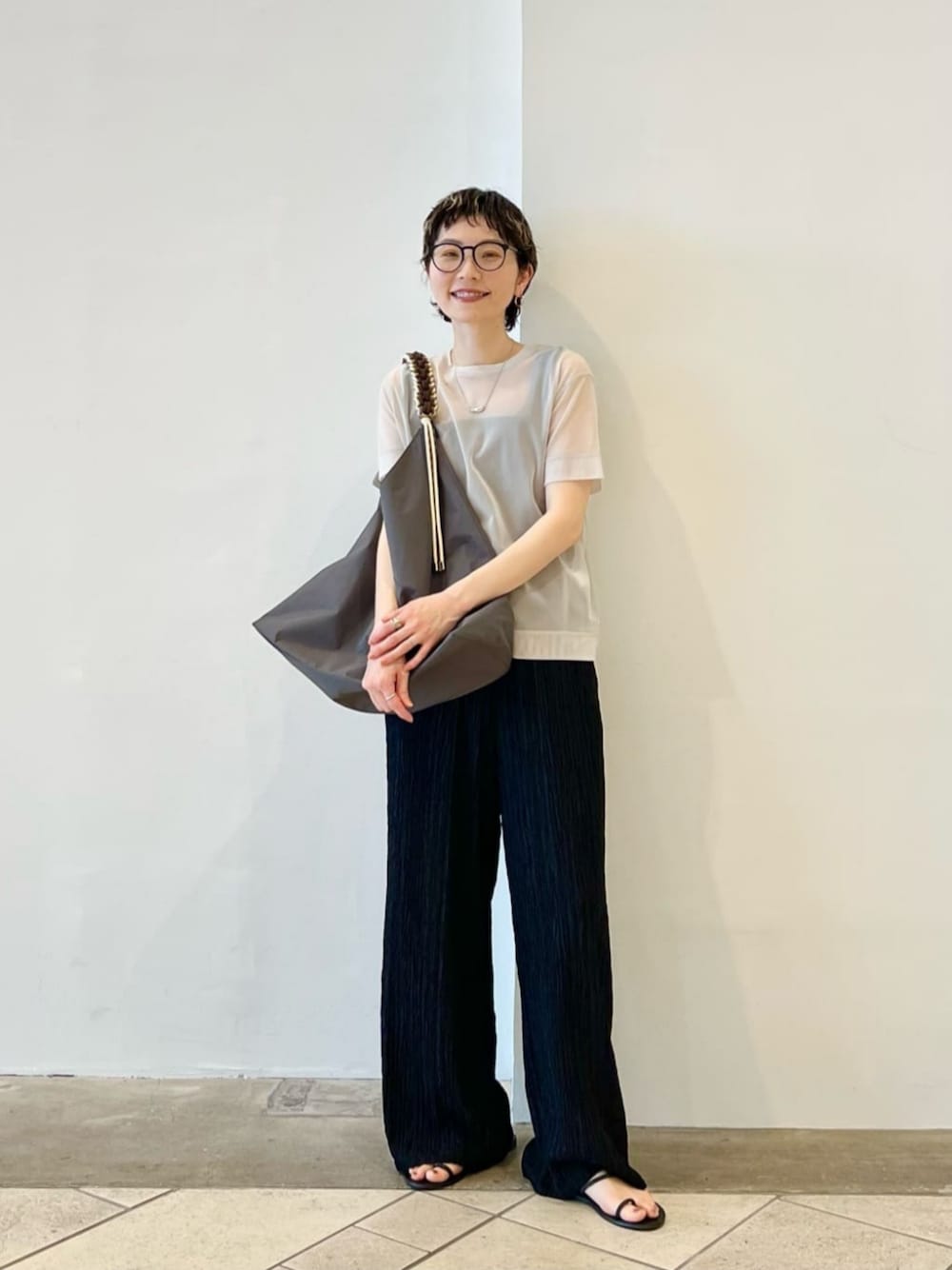 ブラック系のタンクトップ、グレー系のトートバッグ、ベージュ系のTシャツ/カットソーを着用したレディースの春コーディネートの1枚目の写真