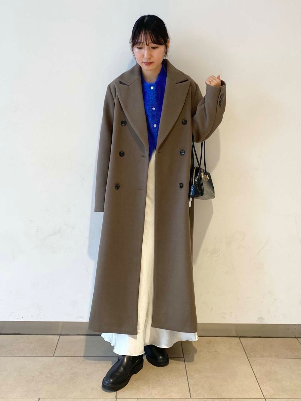 ブルー系のカーディガン/ボレロ、ブラック系のブーツ、ホワイト系のスカートを着用したレディースの冬コーディネートの1枚目の写真