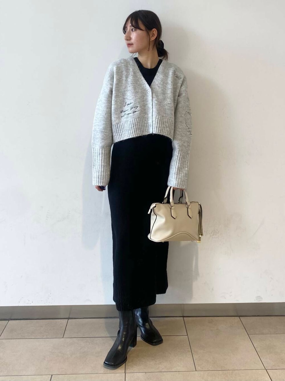 ブラック系のブーツ、グレー系のワンピースを着用したレディースの冬コーディネートの1枚目の写真