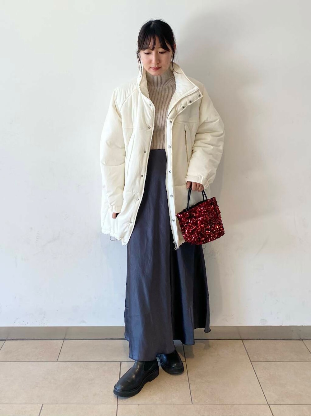 ベージュ系のニット/セーター、ブラック系のブーツ、グレー系のスカートを着用したレディースの秋コーディネートの1枚目の写真