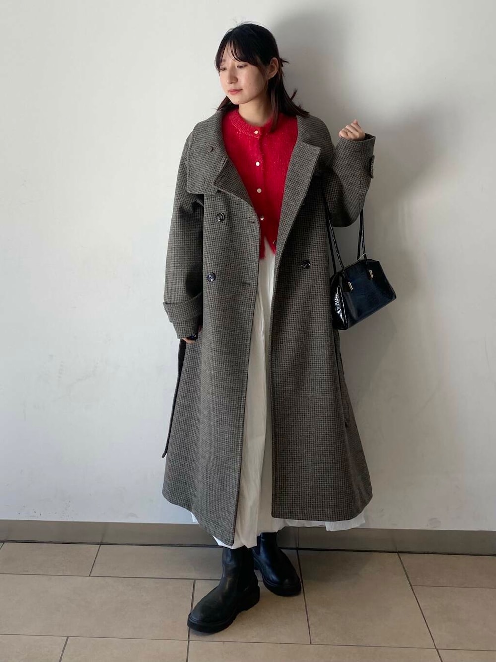 ホワイト系のスカート、ブラック系のブーツ、ブラック系のハンドバッグを着用したレディースの冬コーディネートの1枚目の写真