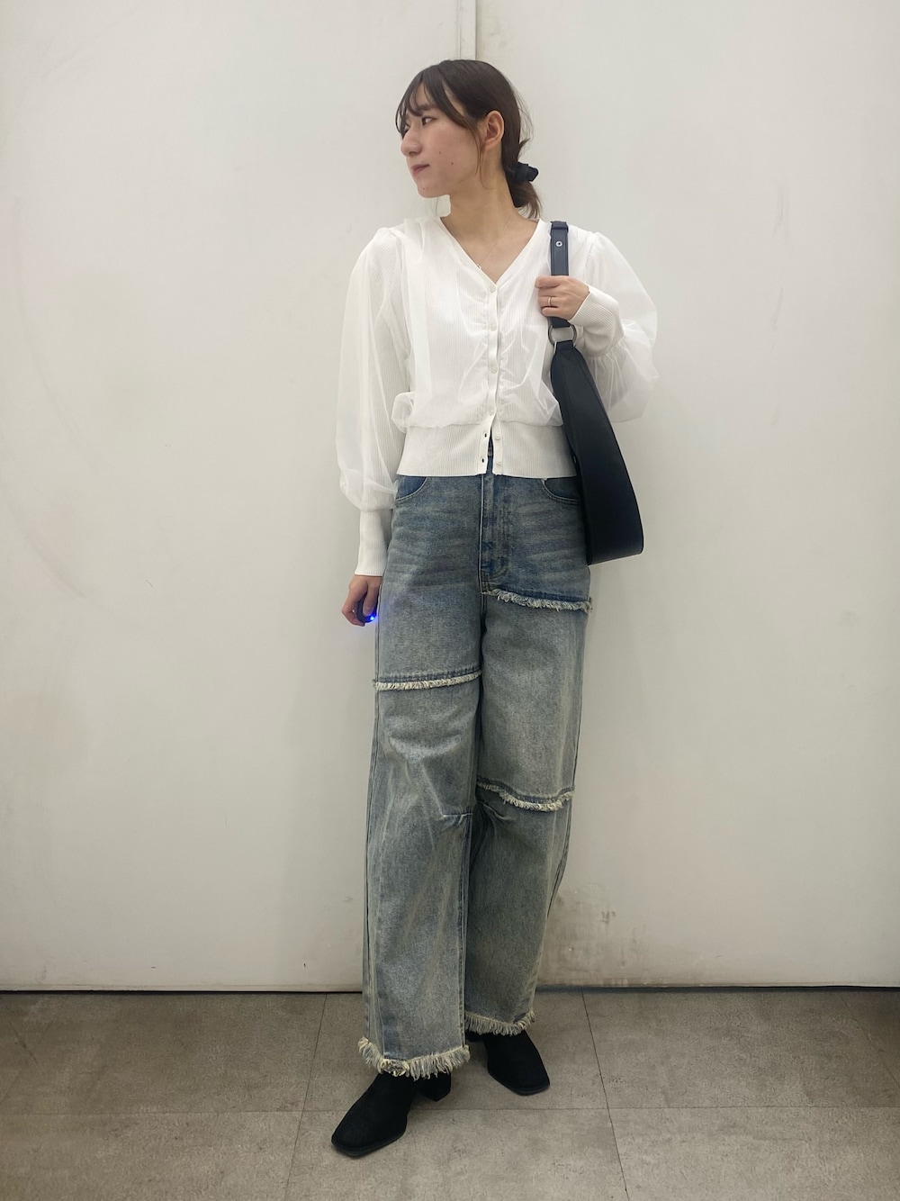 ブルー系のデニムパンツ、ホワイト系のカーディガン/ボレロ、ブラック系のブーツを着用したレディースの冬コーディネートの1枚目の写真