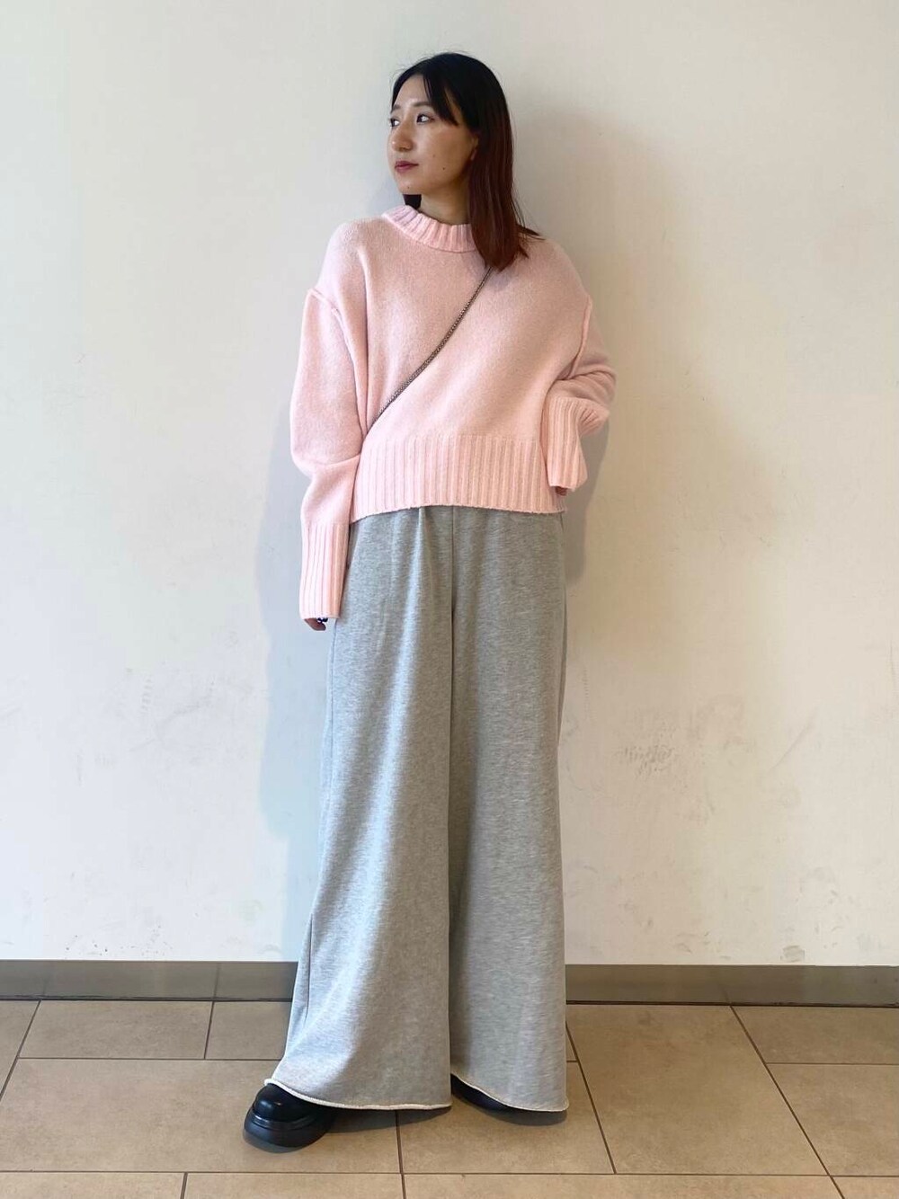 シルバー系のショルダーバッグ、ブラック系のブーツ、グレー系のスウェットパンツを着用したレディースの冬コーディネートの1枚目の写真