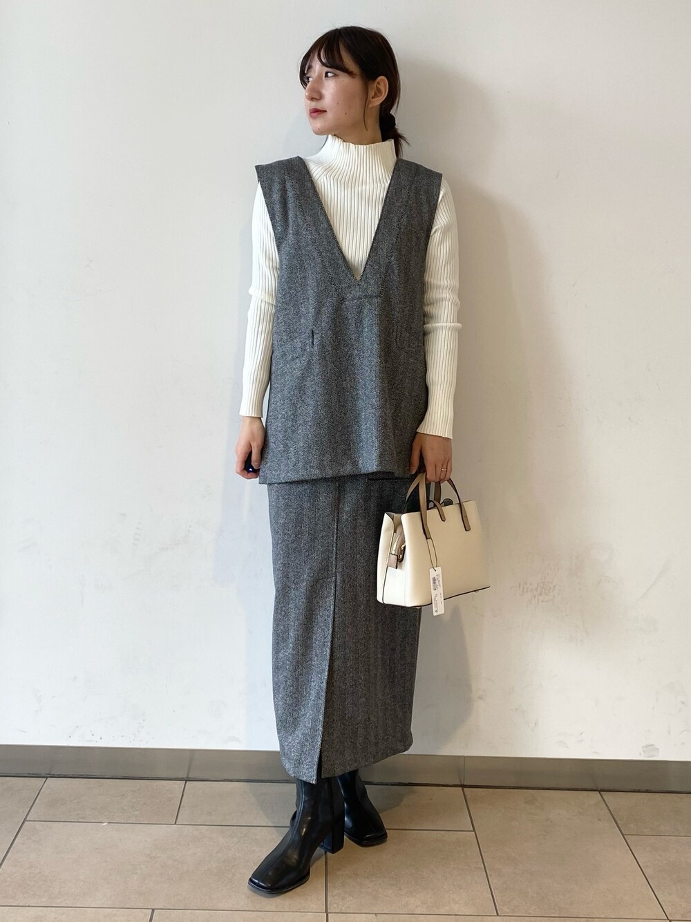 ホワイト系のニット/セーター、ブラック系のブーツ、ブラック系のベストを着用したレディースの冬コーディネートの1枚目の写真