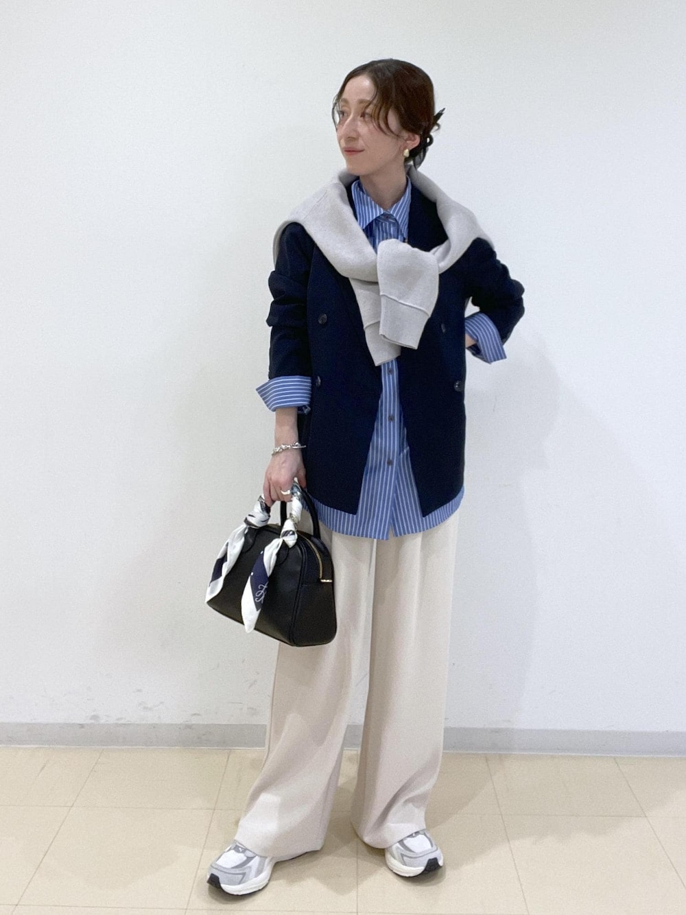 ブルー系のシャツ/ブラウス、グレー系のニット/セーター、ベージュ系のその他パンツを着用したレディースの春コーディネートの1枚目の写真