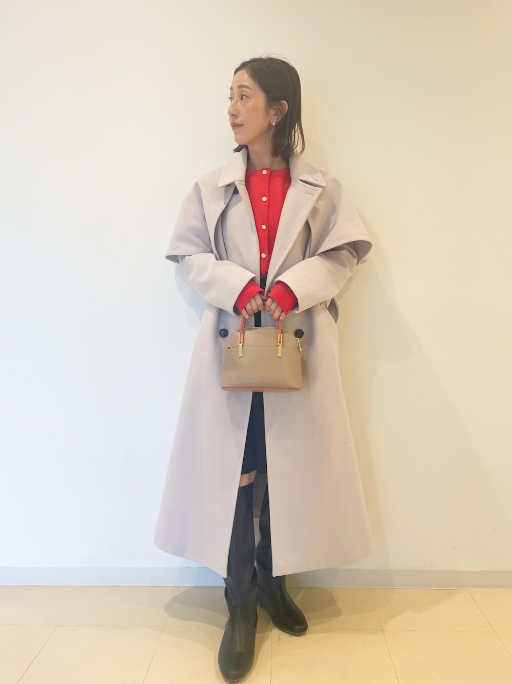 オレンジ系のカーディガン/ボレロ、ブラック系のスカート、ブラック系のブーツを着用したレディースの秋コーディネートの1枚目の写真