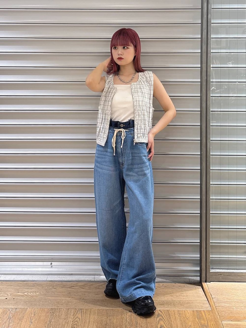 ブルー系のデニムパンツ、ホワイト系のベスト、ブラック系のローファーを着用したレディースの夏コーディネートの1枚目の写真