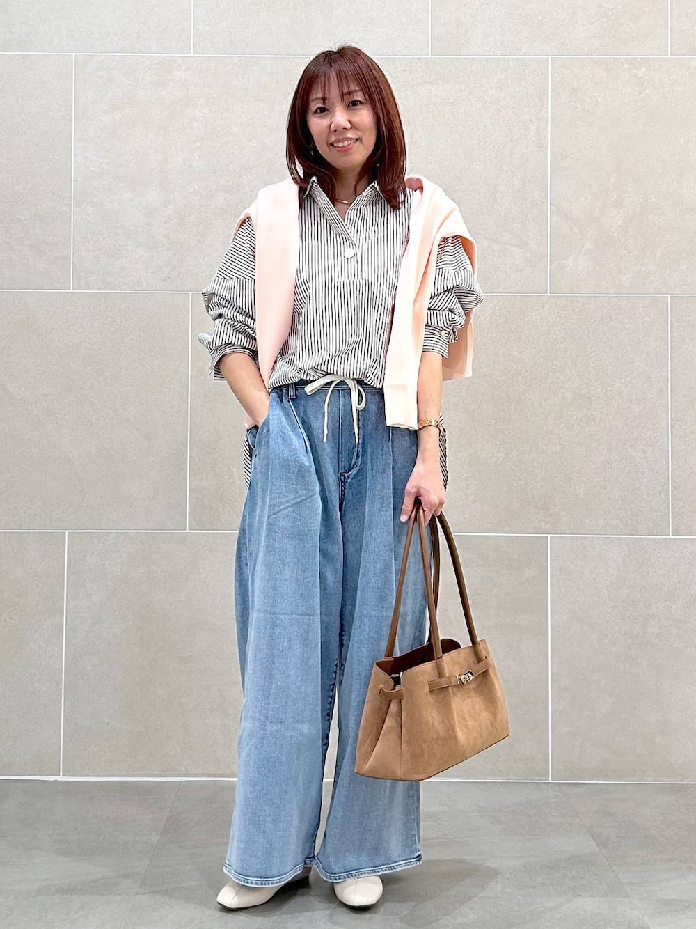 ホワイト系のパンプス、ブルー系のデニムパンツ、イエロー系のハンドバッグを着用したレディースの春コーディネートの1枚目の写真