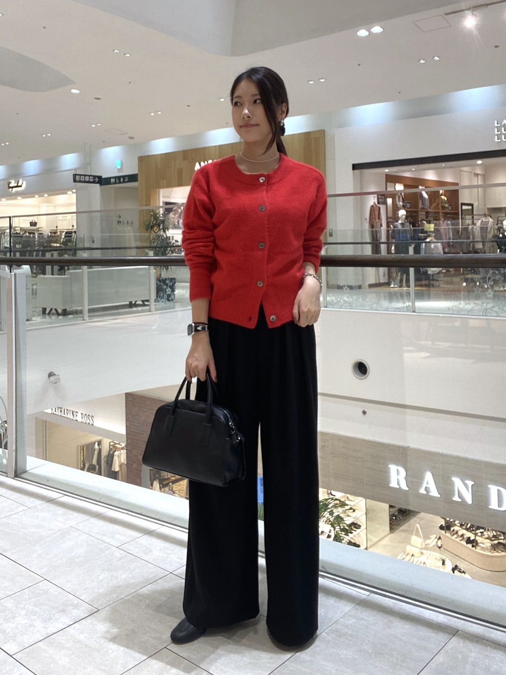 レッド系のカーディガン/ボレロ、ブラック系のスラックス、ブラック系のボストンバッグを着用したレディースの秋コーディネートの1枚目の写真