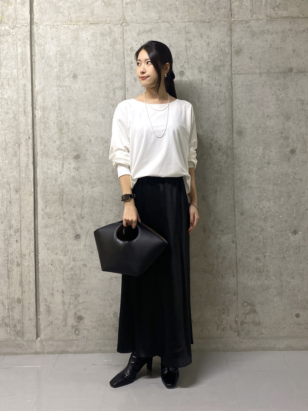 ブラック系のスカート、ホワイト系のTシャツ/カットソー、ブラック系のハンドバッグを着用したレディースの秋コーディネートの1枚目の写真