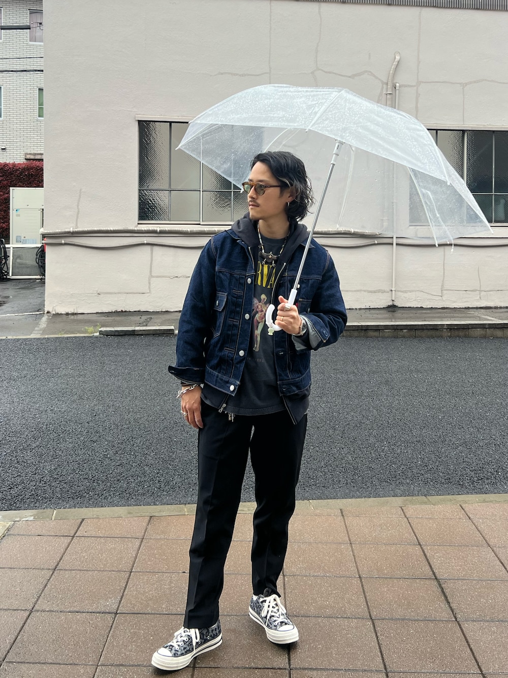 ブルー系のデニムジャケット、ブラック系のスラックス、その他のスニーカーを着用したメンズの春コーディネートの1枚目の写真