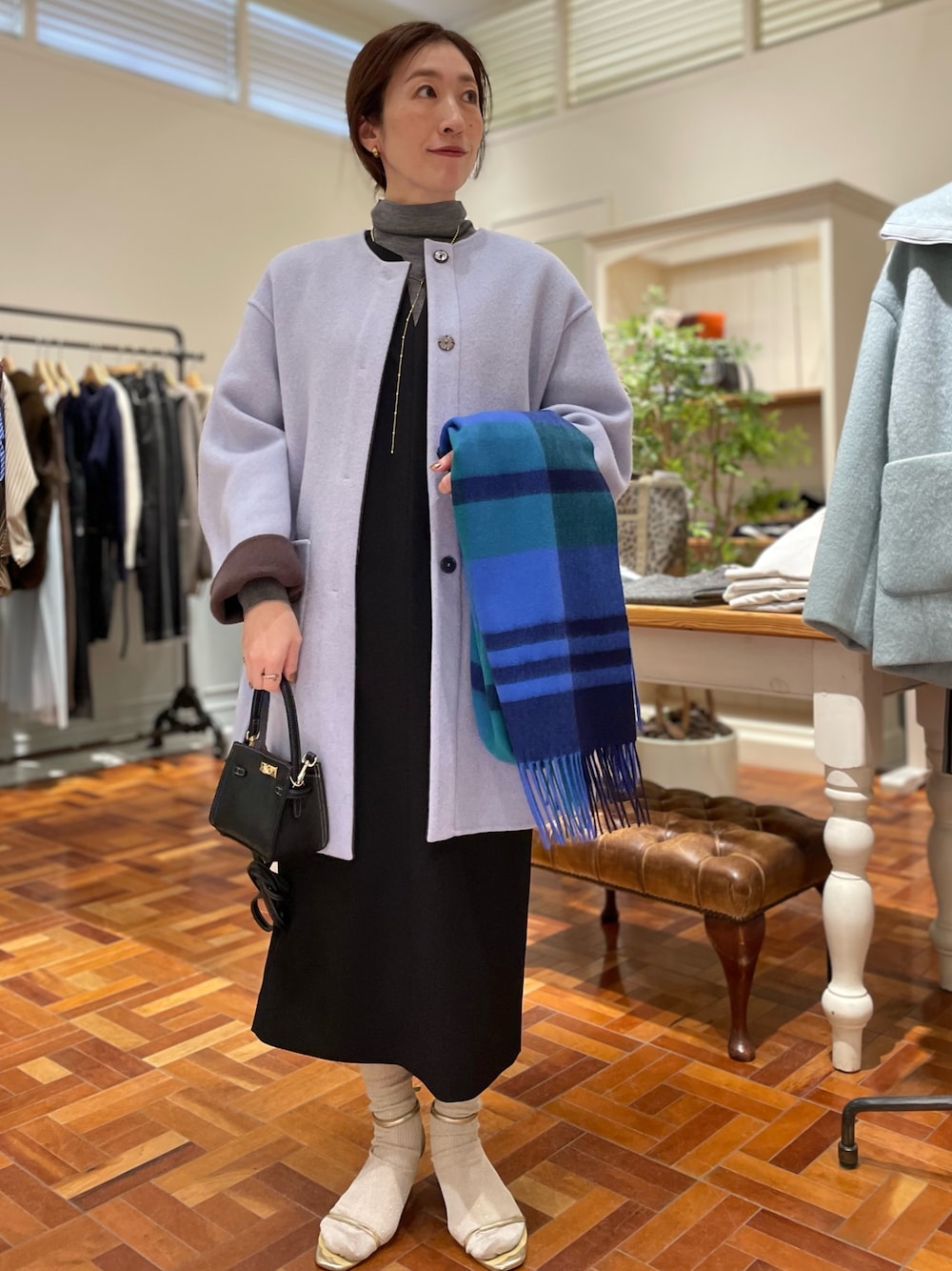 ブラウン系のノーカラーコート、ブラック系のワンピース、グレー系のニット/セーターを着用したレディースの冬コーディネートの1枚目の写真