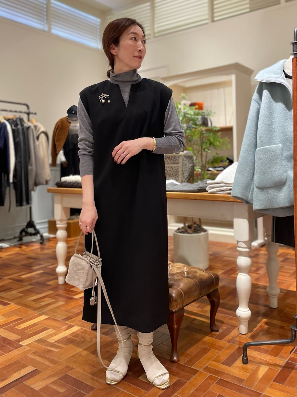 ブラック系のワンピース、グレー系のニット/セーター、ベージュ系のショルダーバッグを着用したレディースの冬コーディネートの1枚目の写真