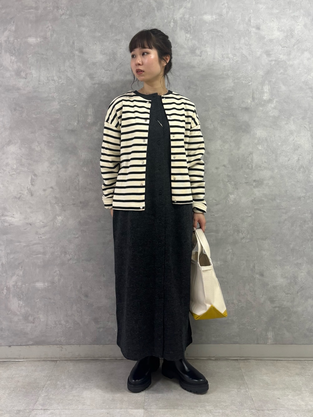 ブラック系のブーツ、ホワイト系のトートバッグ、グレー系のワンピースを着用したレディースの秋コーディネートの1枚目の写真