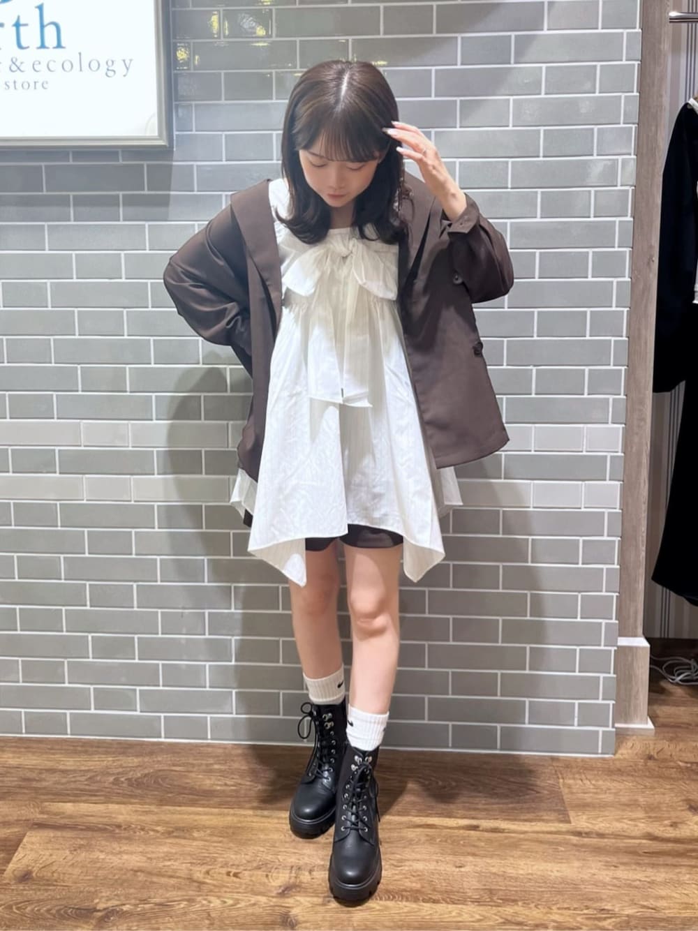 ブラック系のブーツ、ホワイト系のチュニック、ブラウン系のブルゾンを着用したレディースの秋コーディネートの1枚目の写真