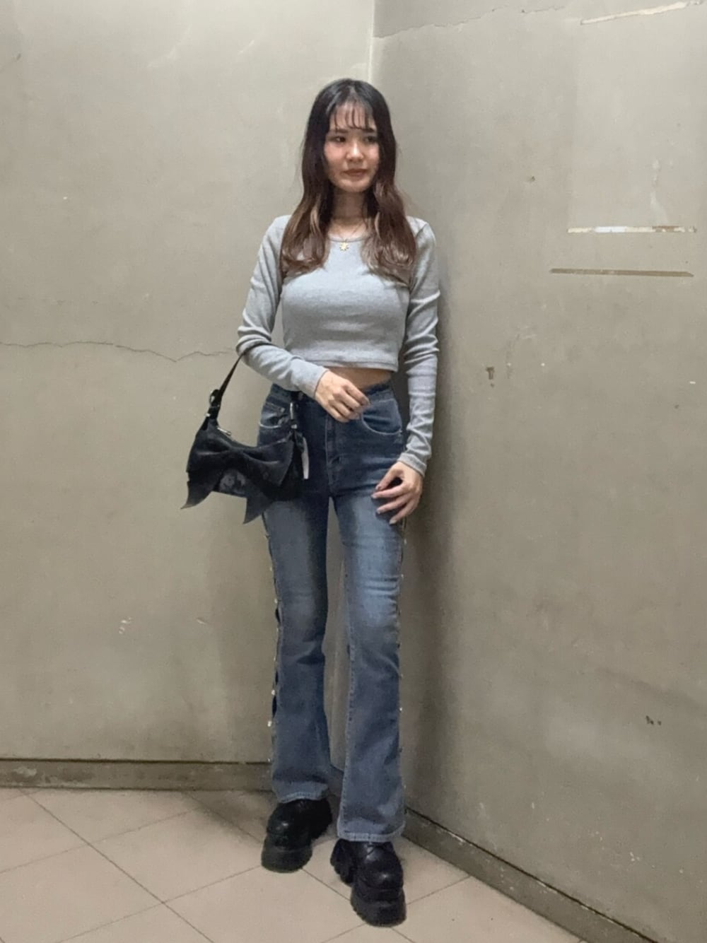 ブラック系のブーツ、グレー系のTシャツ/カットソー、ブラック系のハンドバッグを着用したレディースの秋コーディネートの1枚目の写真