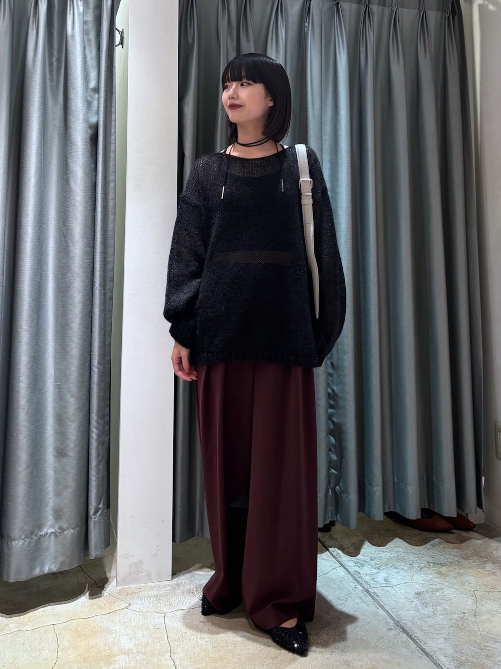 ブラック系のニット/セーター、レッド系のスラックス、グレー系のショルダーバッグを着用したレディースの秋コーディネートの1枚目の写真