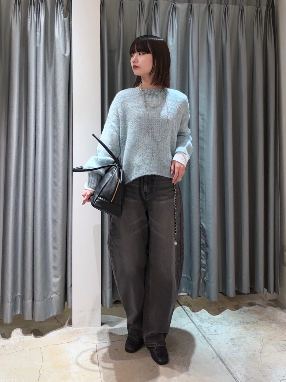 ブルー系のニット/セーター、ブラック系のデニムパンツ、ホワイト系のTシャツ/カットソーを着用したレディースの秋コーディネートの1枚目の写真