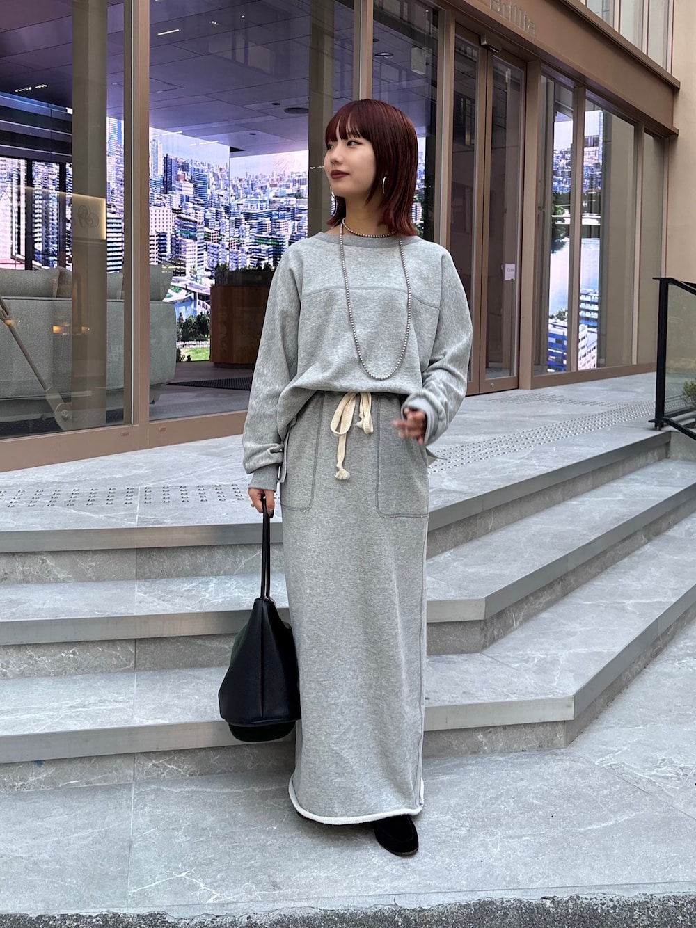 グレー系のスカート、グレー系のスウェット、ブラック系のショルダーバッグを着用したレディースの秋コーディネートの1枚目の写真