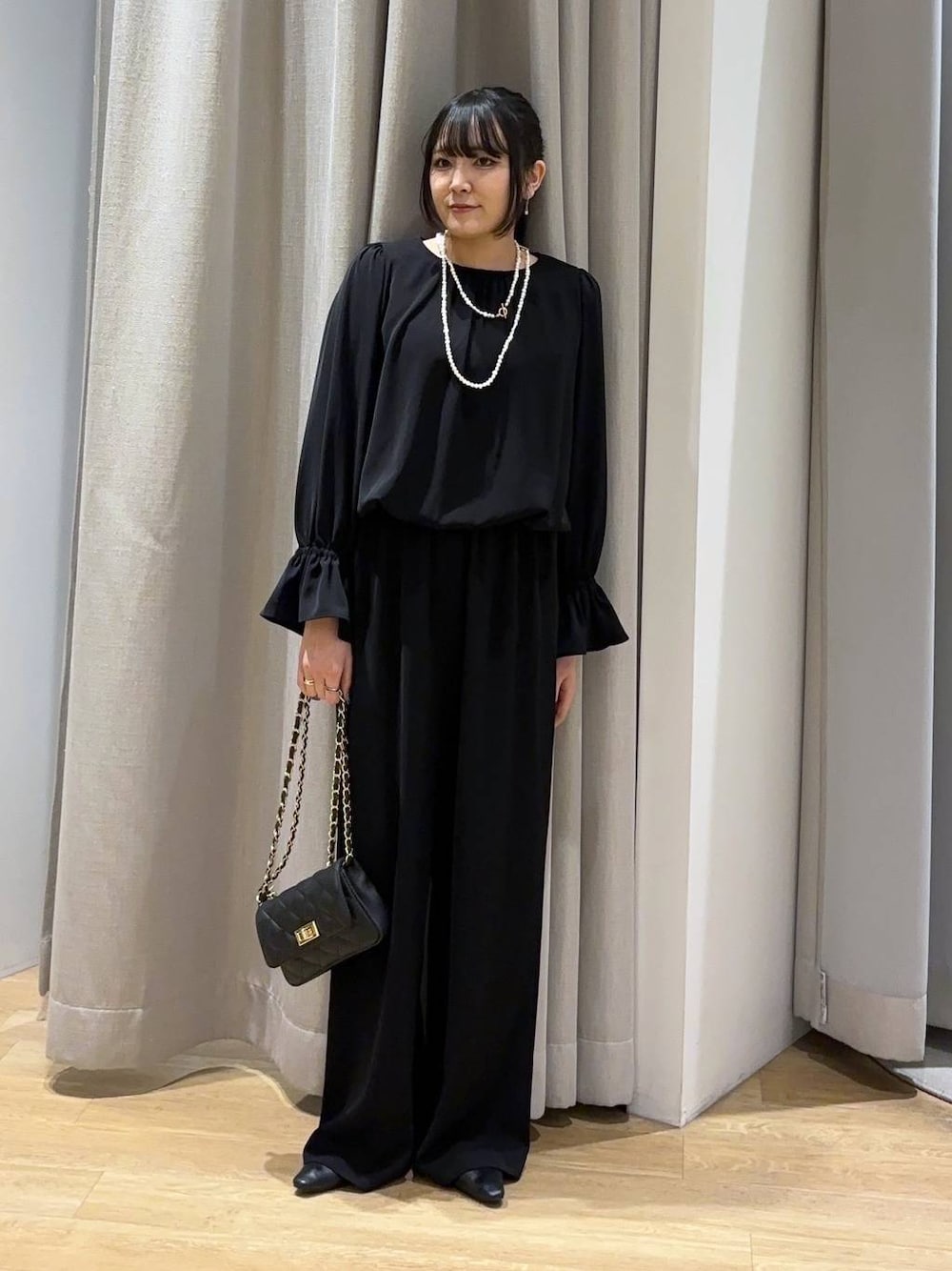 ブラック系のつなぎ/オールインワン、ブラック系のショルダーバッグ、ブラック系のパンプスを着用したレディースの冬コーディネートの1枚目の写真