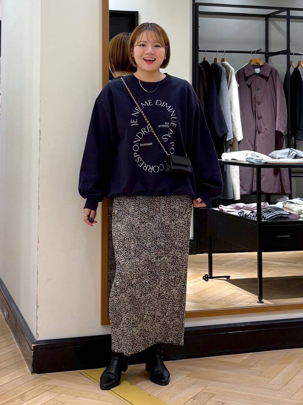 ブラック系のブーツ、ベージュ系のスカート、ブルー系のスウェットを着用したレディースの秋コーディネートの1枚目の写真