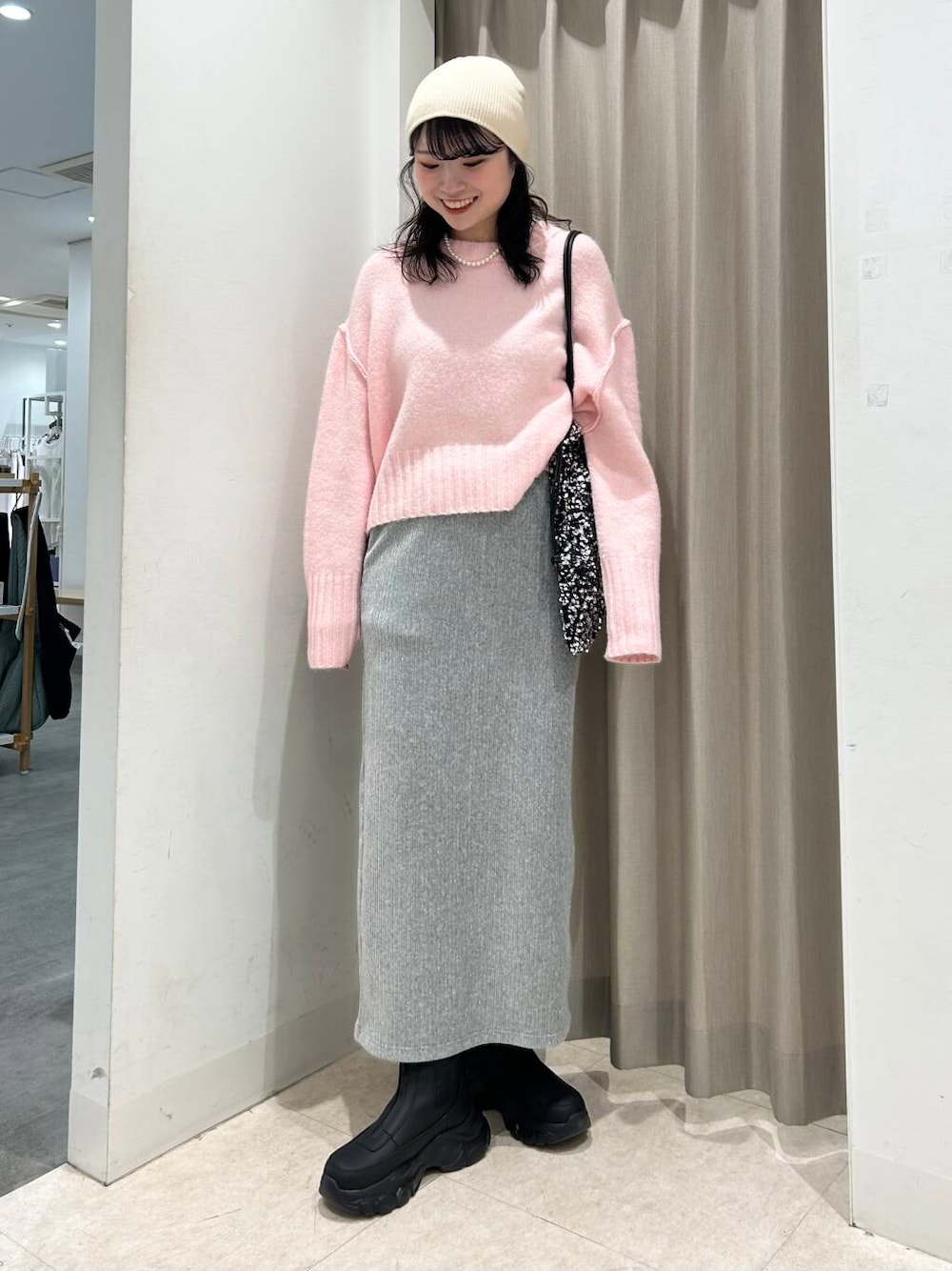 シルバー系のトートバッグ、グレー系のスカート、ブラック系のブーツを着用したレディースの冬コーディネートの1枚目の写真