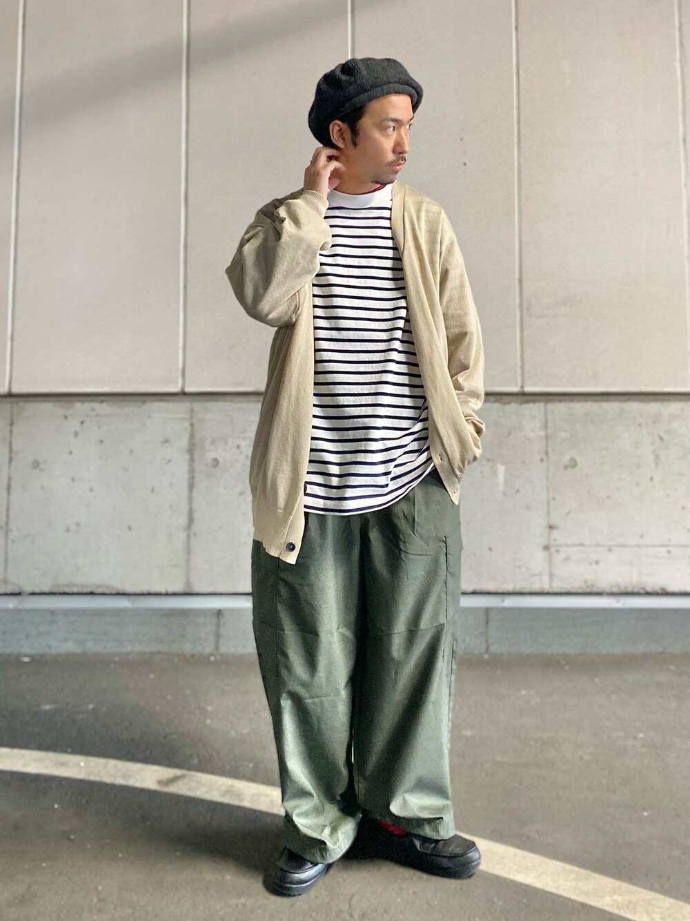 グリーン系のカーゴパンツ、ブラック系のスリッポン、ホワイト系のTシャツ/カットソーを着用したメンズの春コーディネートの1枚目の写真