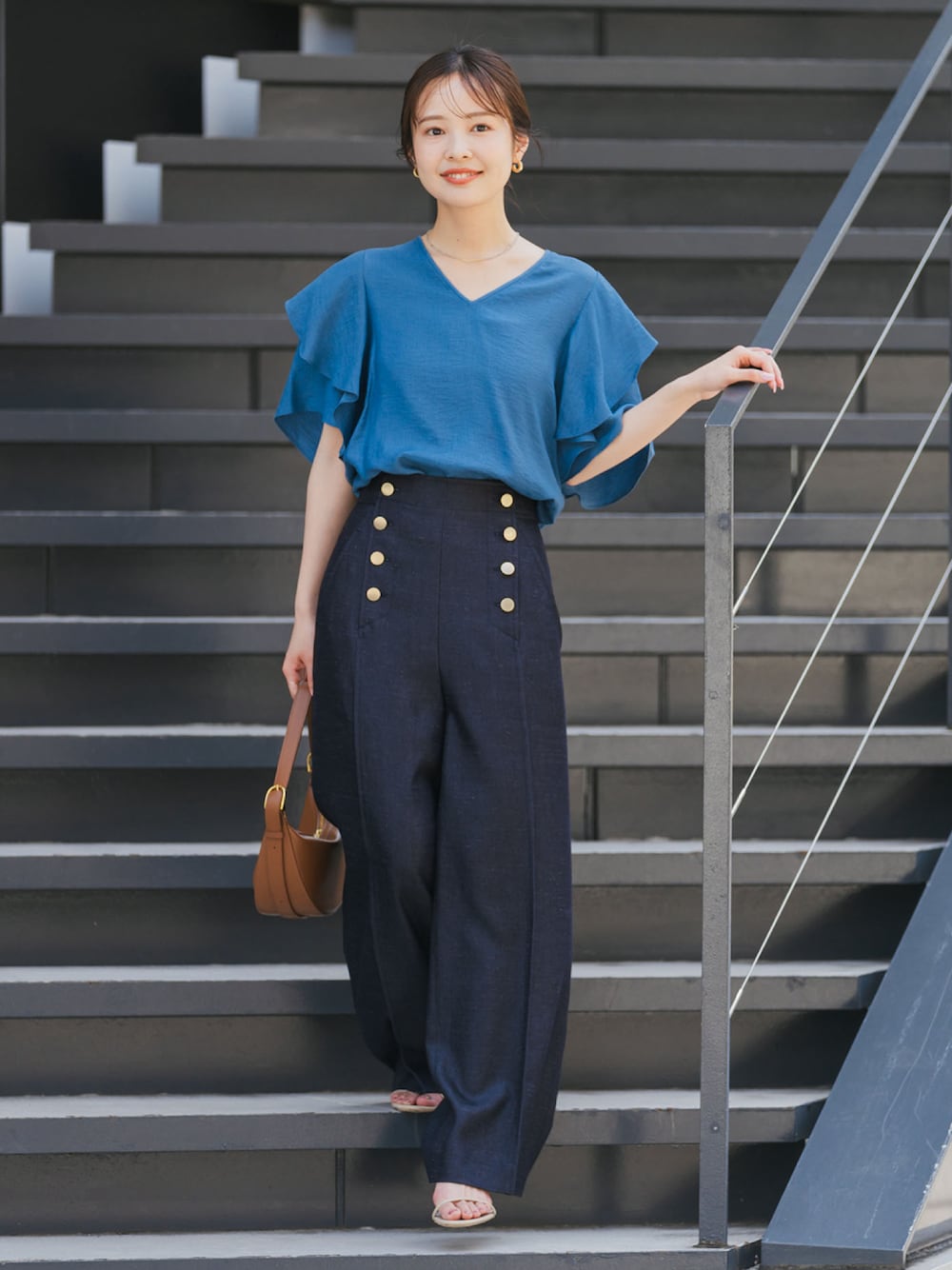 ブルー系のシャツ/ブラウス、ブルー系のスラックス、ブラウン系のハンドバッグを着用したレディースの夏コーディネートの1枚目の写真