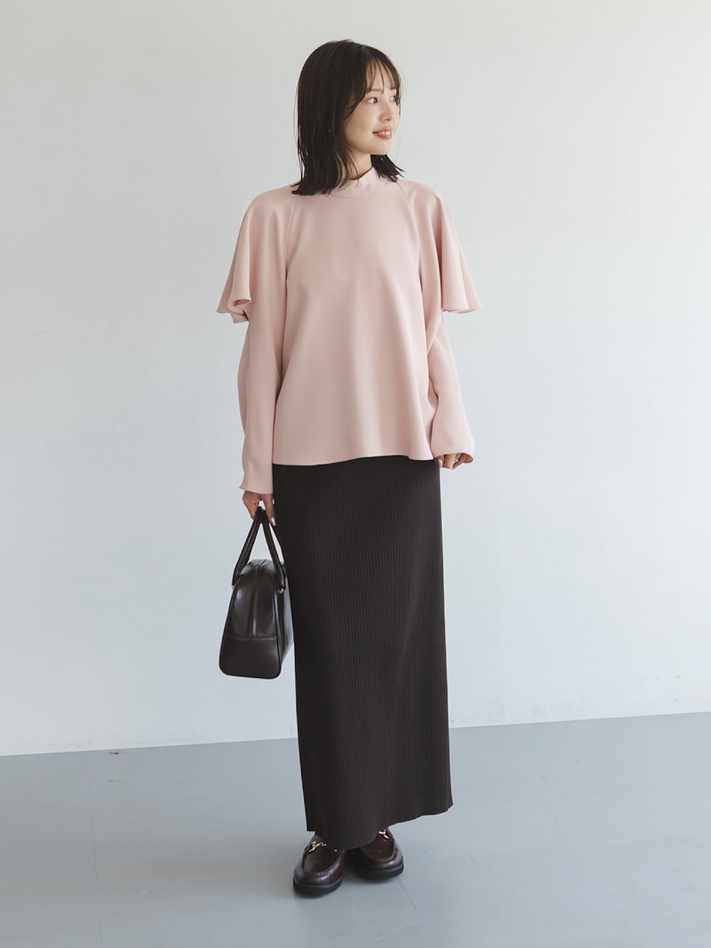 ピンク系のシャツ/ブラウス、ブラウン系のスカート、ブラウン系のハンドバッグを着用したレディースの秋コーディネートの1枚目の写真