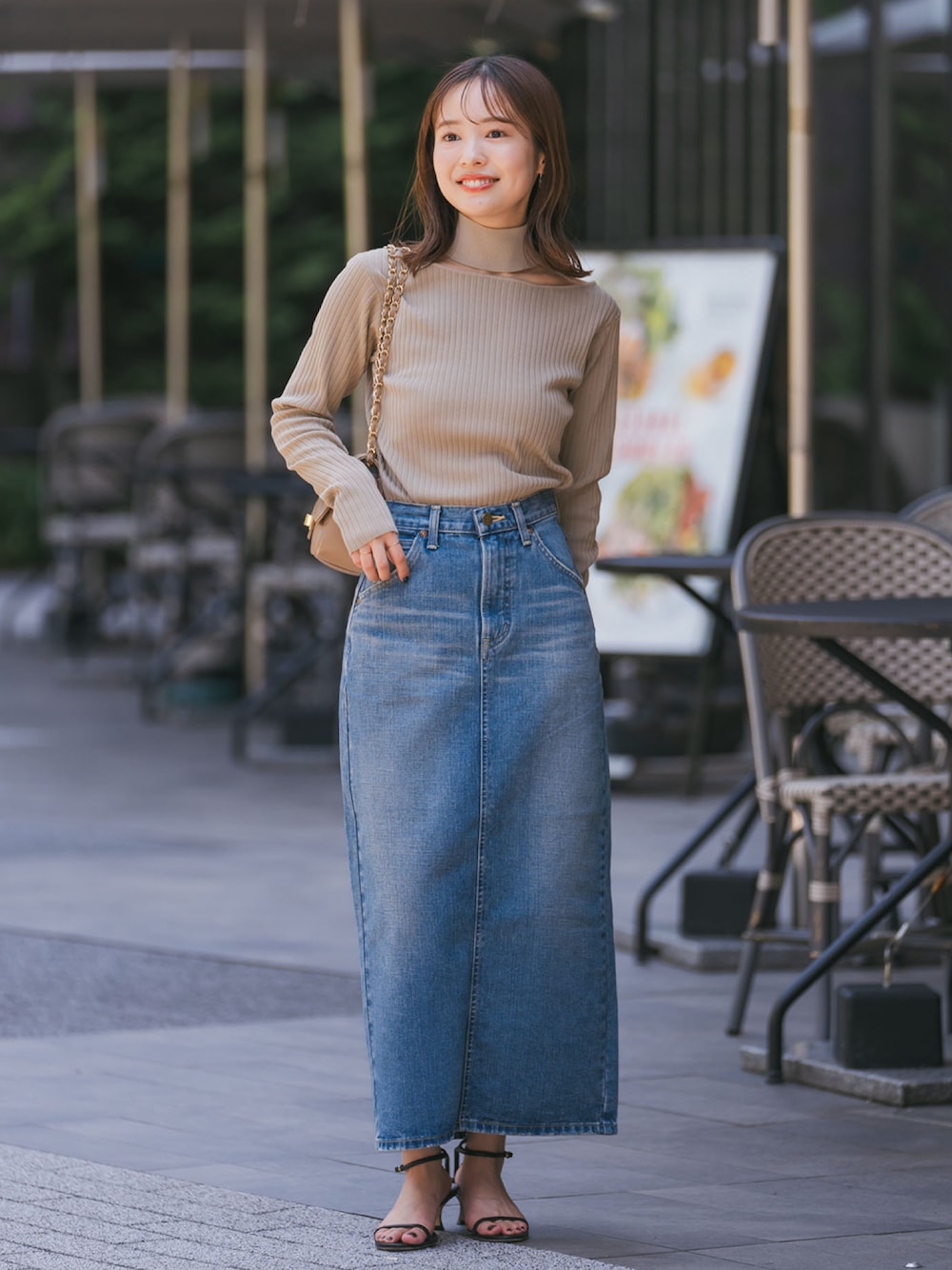 グリーン系のニット/セーター、ブルー系のデニムスカート、ブラック系のサンダルを着用したレディースの夏コーディネートの1枚目の写真