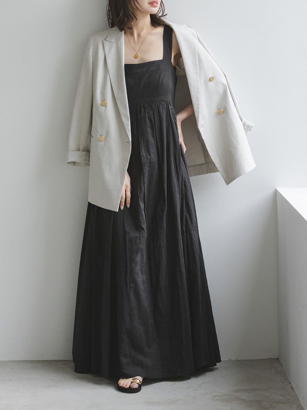 ブラック系のワンピース、グレー系のテーラードジャケット、ブラック系のサンダルを着用したレディースの春コーディネートの1枚目の写真