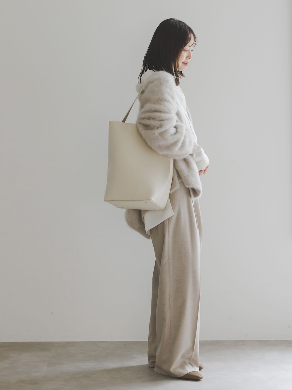 ベージュ系のスラックス、ホワイト系のシャツ/ブラウス、ベージュ系のカーディガン/ボレロを着用したレディースの秋コーディネートの1枚目の写真