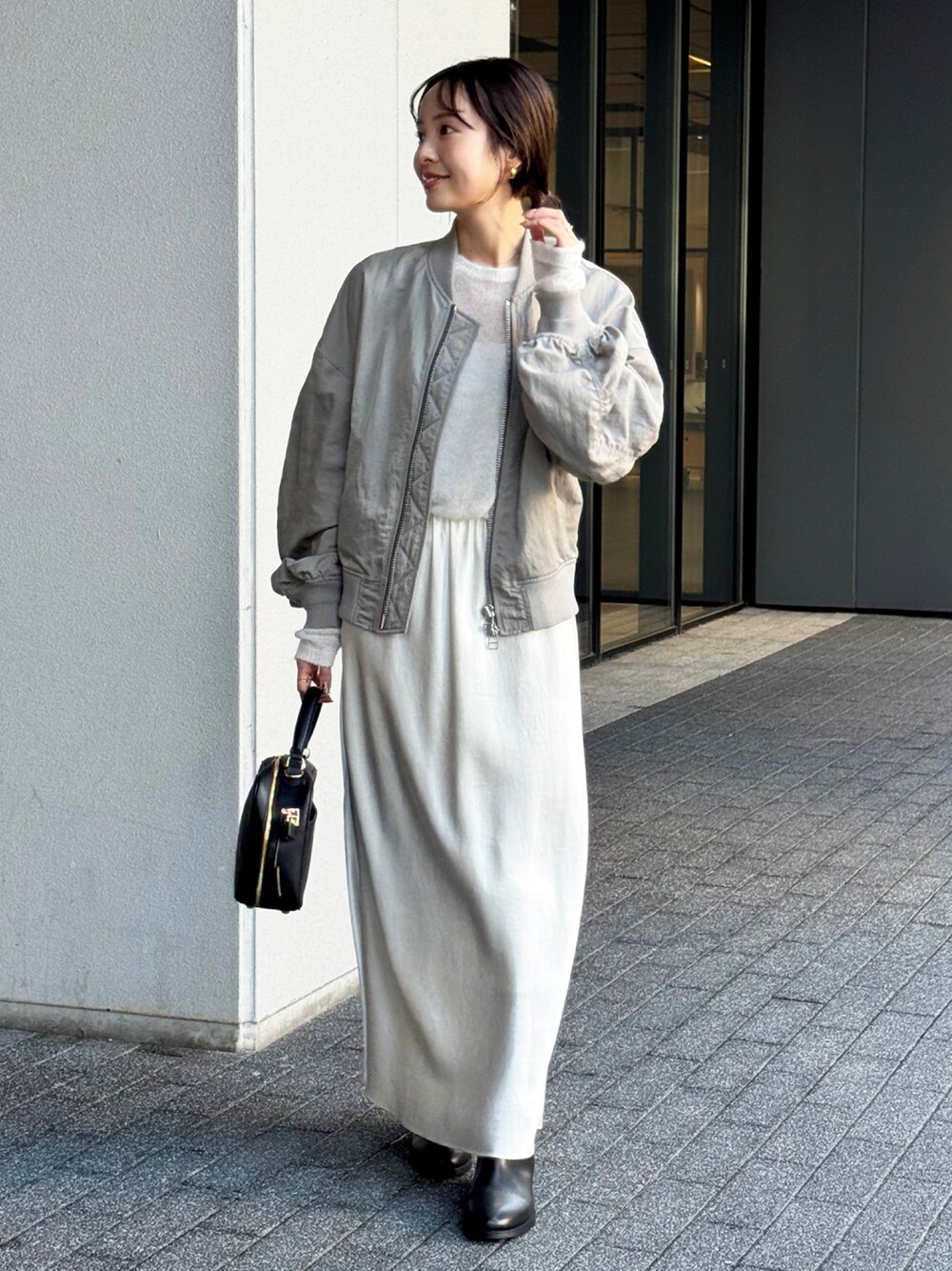 グレー系のMA-1、ホワイト系のニット/セーター、ホワイト系のスカートを着用したレディースの秋コーディネートの1枚目の写真
