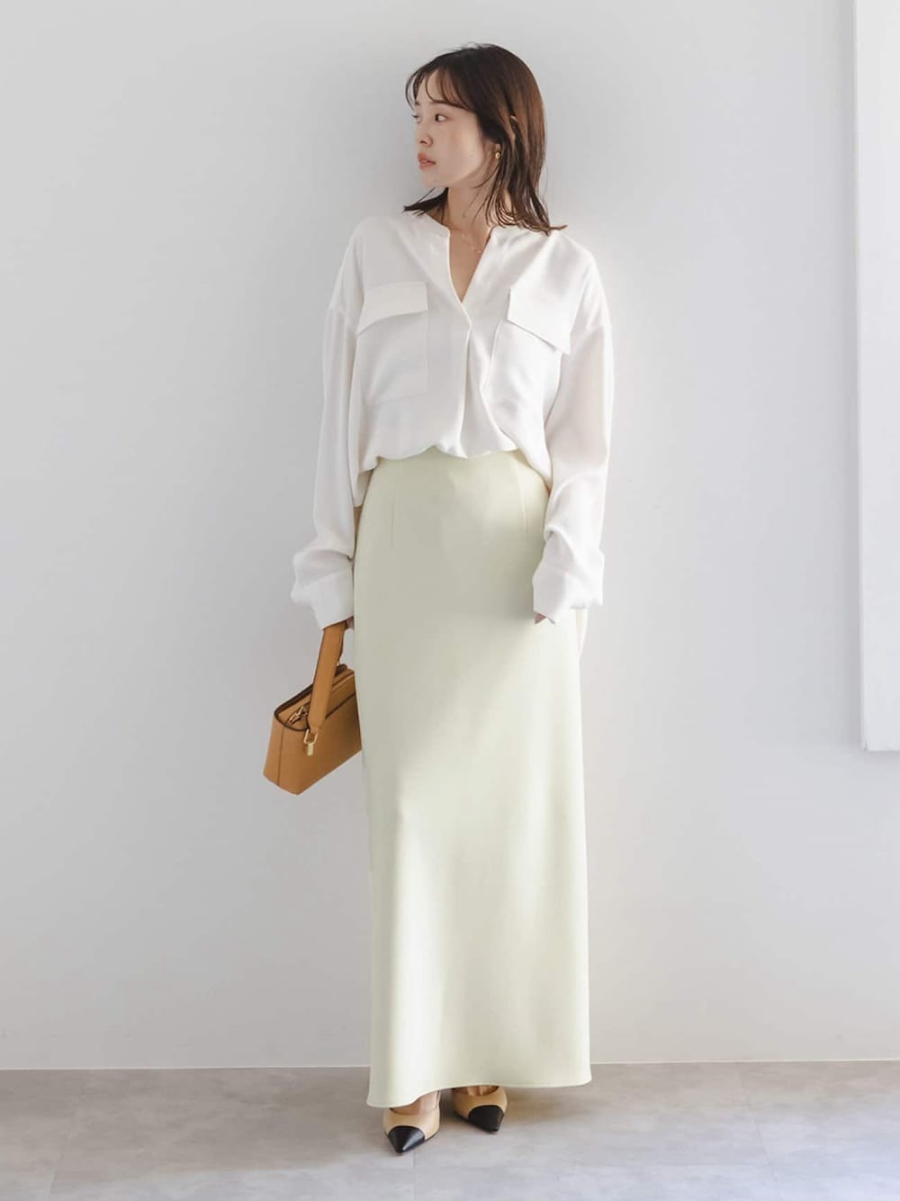 イエロー系のスカート、ホワイト系のシャツ/ブラウス、イエロー系のショルダーバッグを着用したレディースの冬コーディネートの1枚目の写真