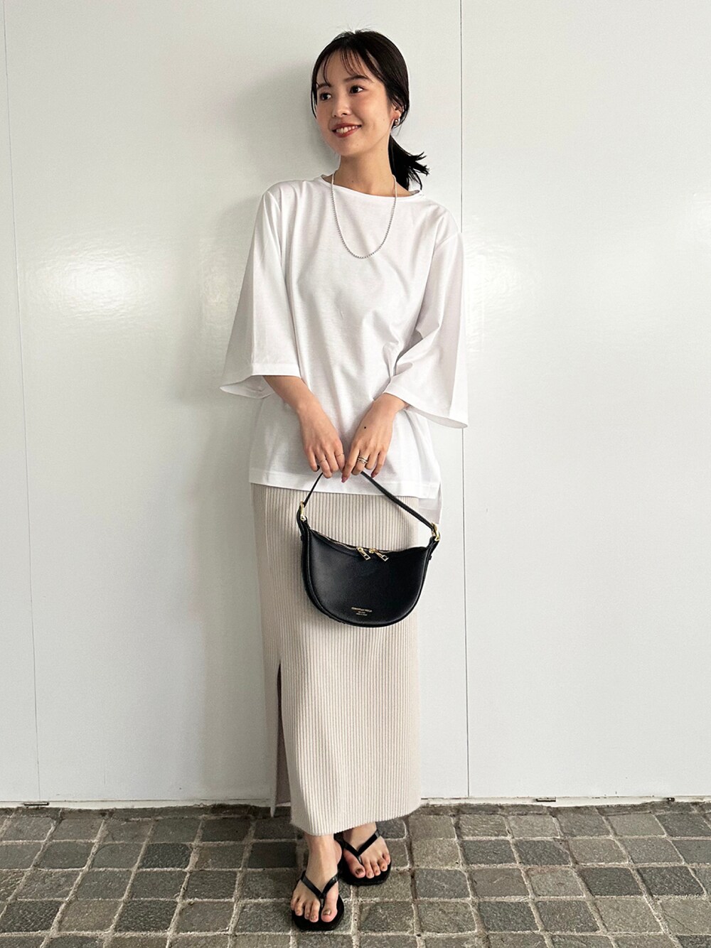 ホワイト系のTシャツ/カットソー、グレー系のスカート、ブラック系のハンドバッグを着用したレディースの春コーディネートの1枚目の写真